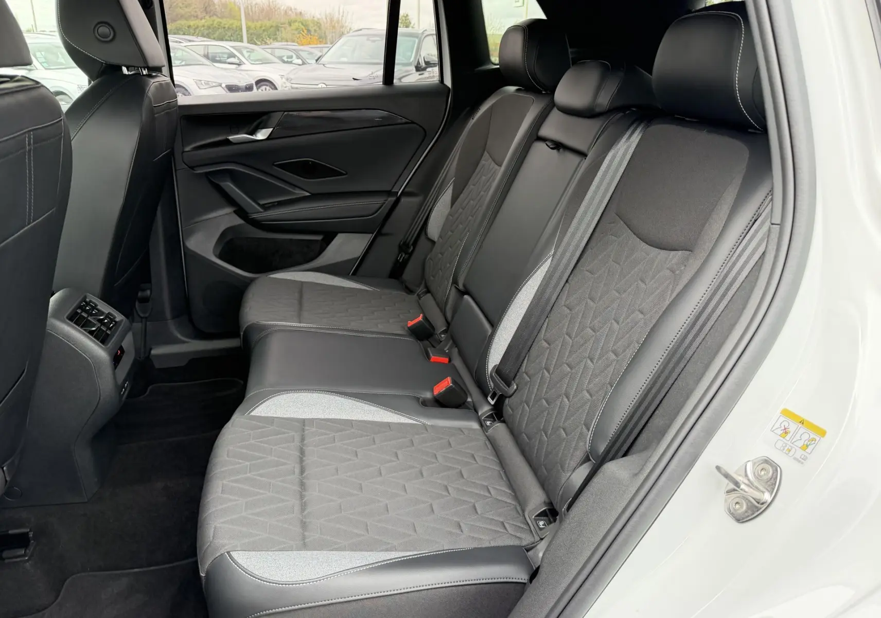 Vue intérieure côté droit des sièges arrière gris et noirs du Volkswagen Tiguan blanc, avec détails de couture apparents.