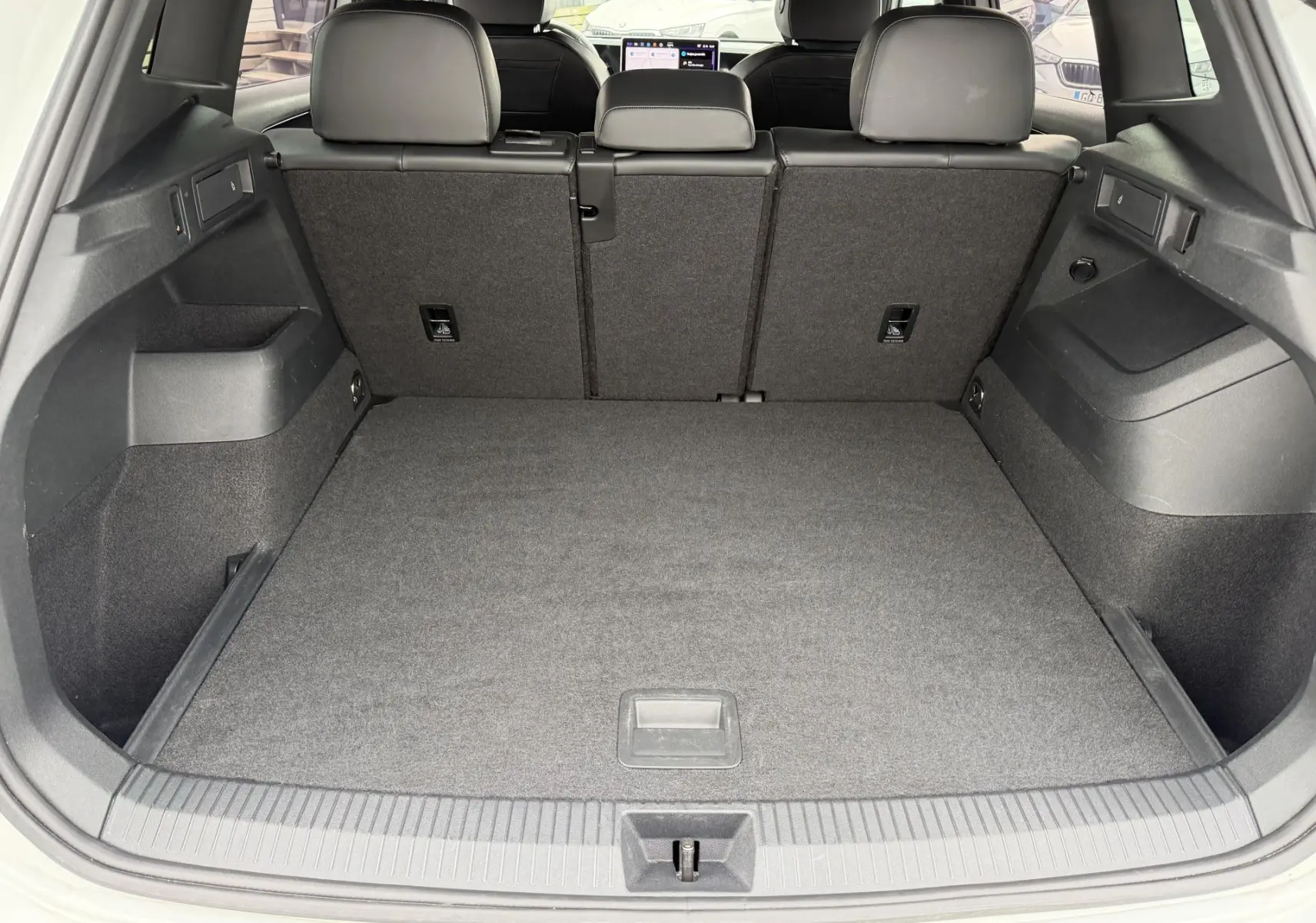 Coffre ouvert vu de l'arrière d'un Volkswagen Tiguan blanc, montrant un espace de chargement propre et spacieux.