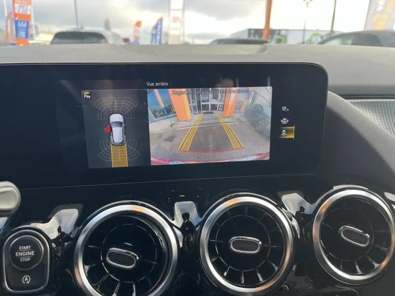 Écran tactile intérieur du Mercedes GLA 200 Business Line montrant la caméra de recul avec vue arrière du véhicule rouge Patagonie métallisé designo.