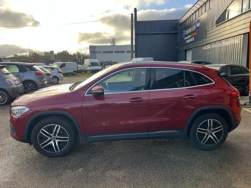 Profil côté gauche d'un Mercedes GLA 200 Business Line rouge Patagonie métallisé avec jantes alliage cinq branches.