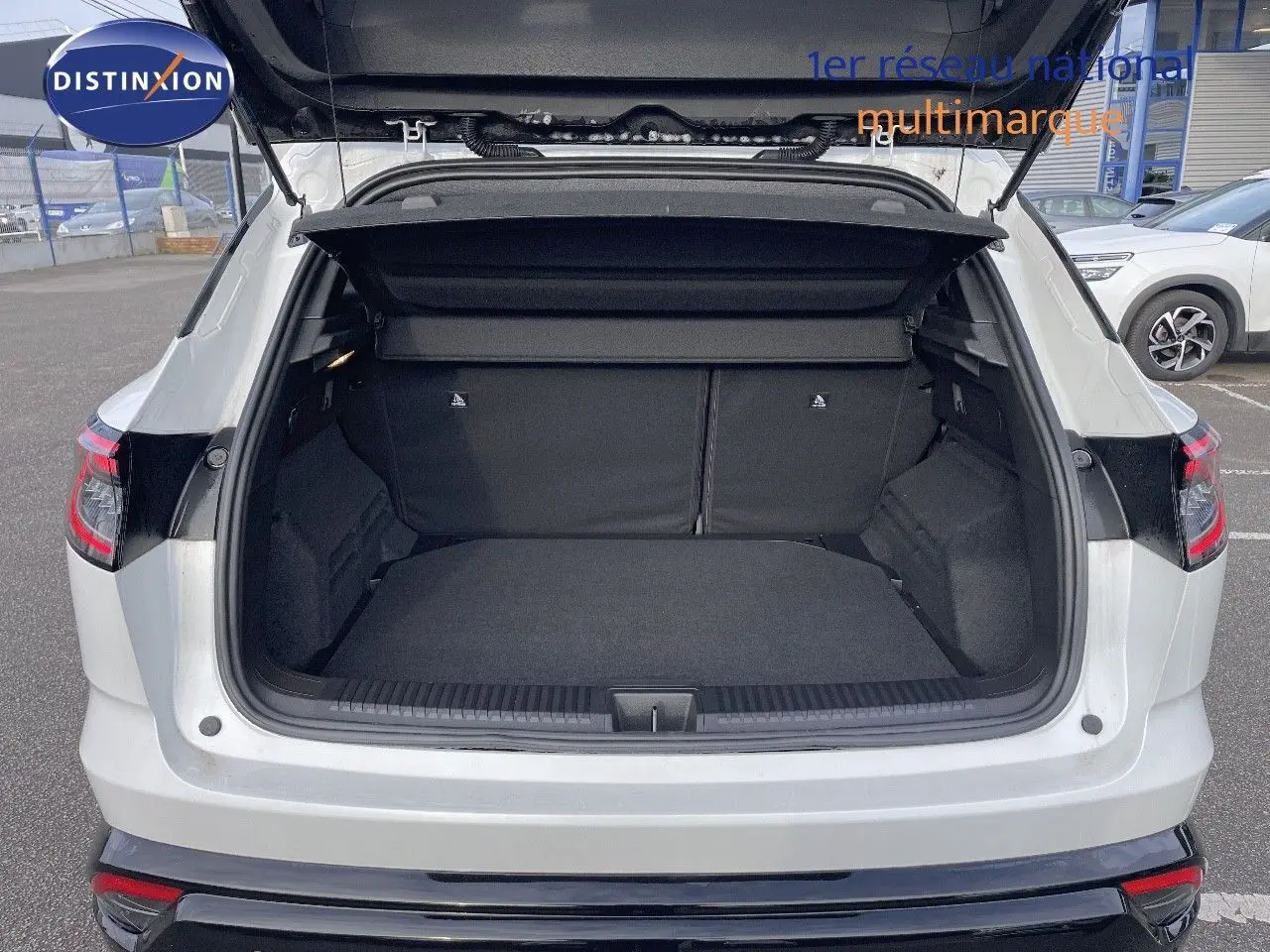 Coffre ouvert vu de l'arrière d'un Renault Austral blanc nacré, soulignant l'espace de chargement généreux.