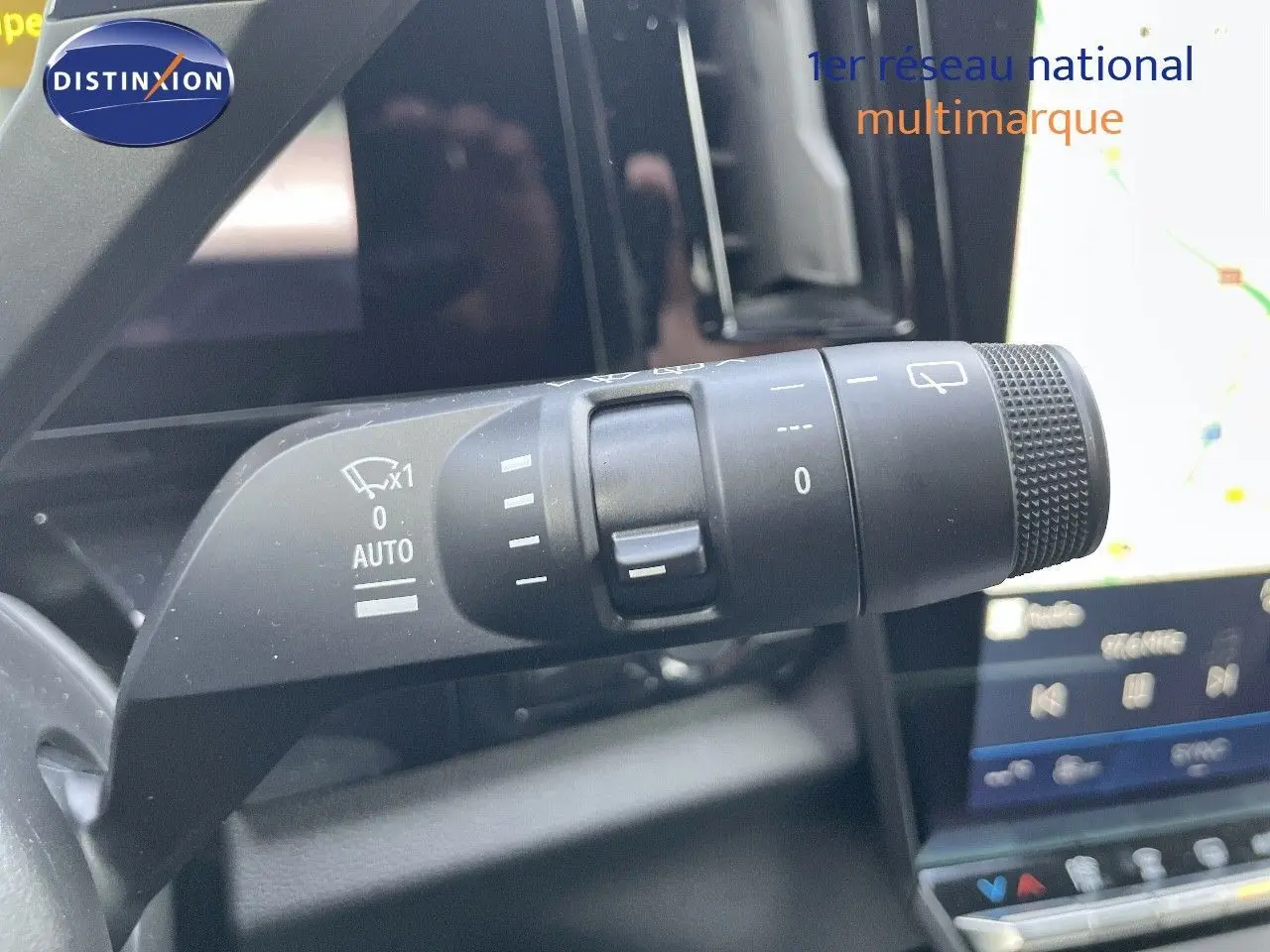 Gros plan sur la commande d’essuie-glace du Renault Austral blanc nacré, avec écran tactile en arrière-plan.