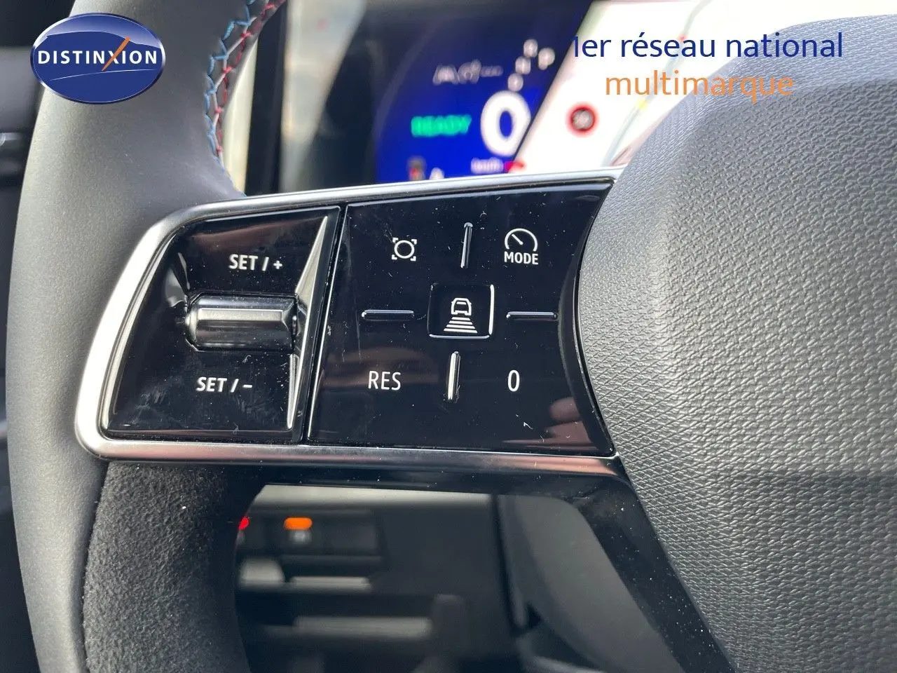 Gros plan sur les commandes au volant du Renault Austral E-Tech hybride 2025, avec affichage numérique en arrière-plan.