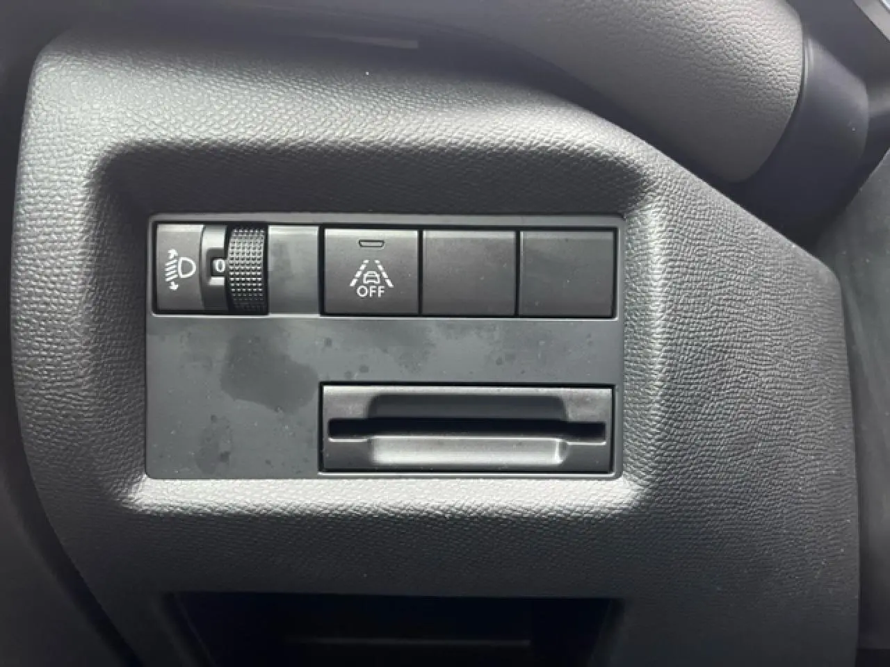 Gros plan sur les commandes de réglage des feux et de l'aide à la conduite du tableau de bord du Citroën C5 Aircross gris.