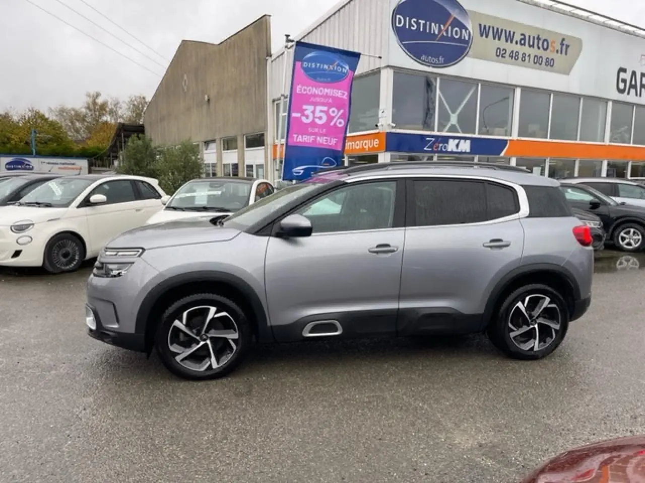 Profil côté gauche d'un Citroën C5 Aircross gris Artense 2021 avec jantes alliage 18'' Swirl sur parking extérieur.