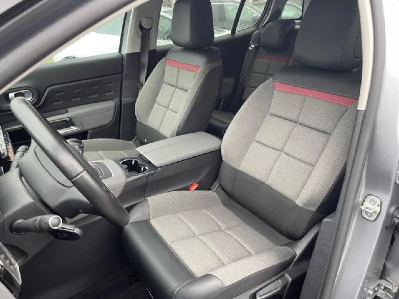 Vue intérieure côté conducteur du Citroën C5 Aircross gris Artense, sièges tissu gris avec bande rouge et cuir noir.
