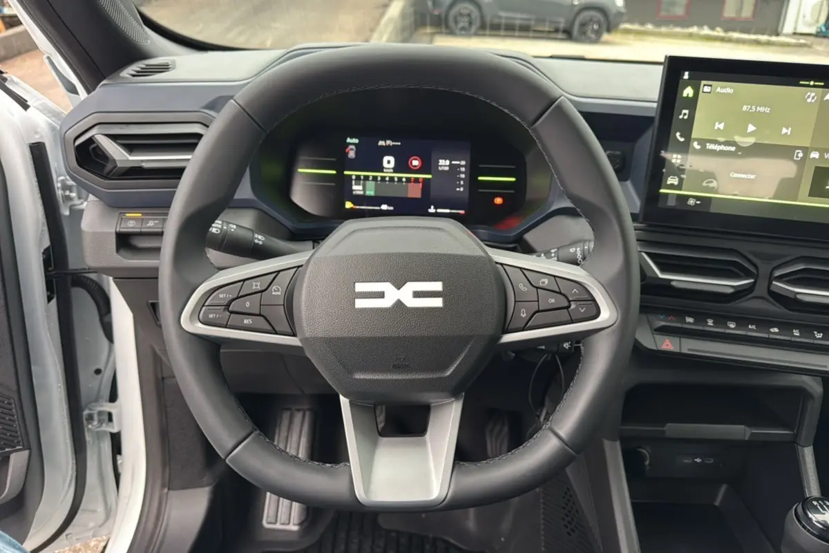 Vue centrée sur le volant et le tableau de bord numérique du Dacia Duster 2025, intérieur moderne et épuré.
