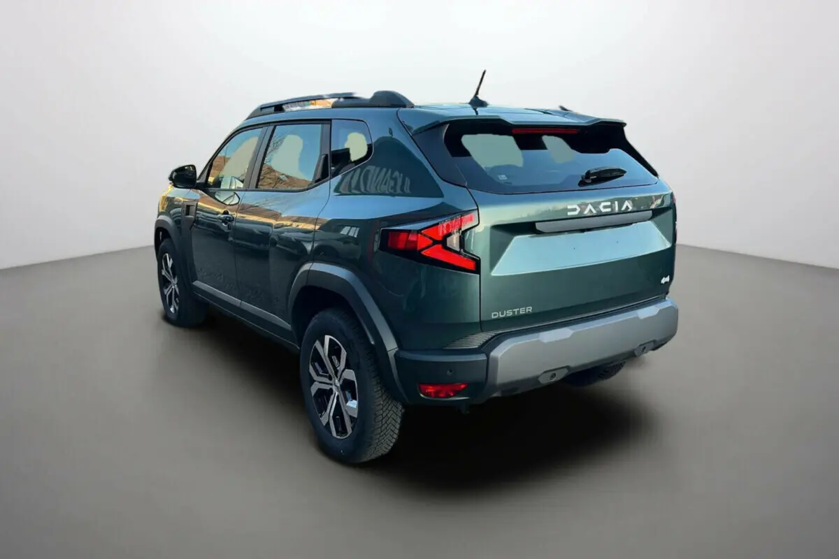 Vue 3/4 arrière du Dacia Duster 2025 vert cèdre avec logo DACIA et feux arrière en forme de flèche rouge.