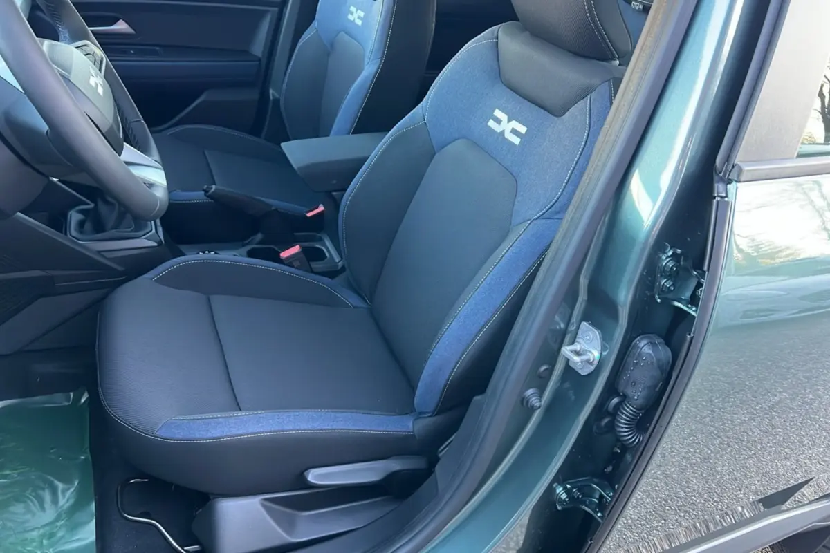 Vue intérieure côté conducteur du Dacia Duster 2025 vert cèdre, sièges bi-matière avec logo distinctif brodé.