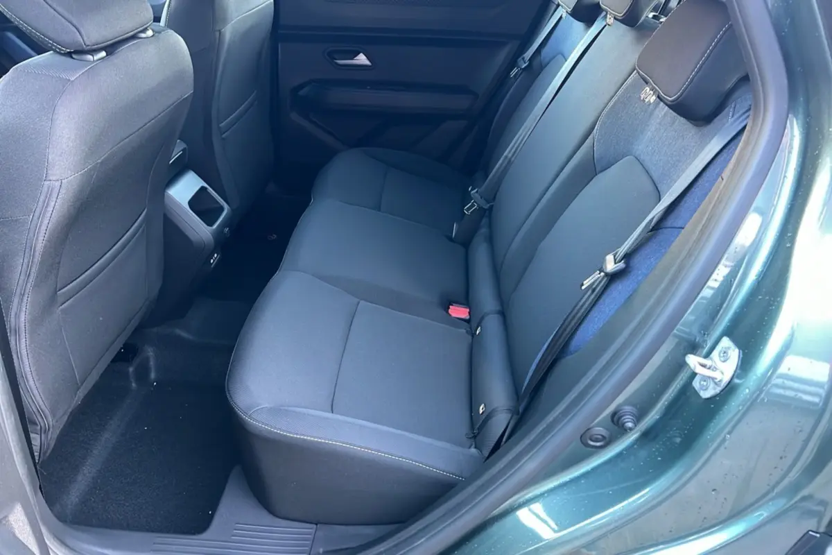 Vue intérieure arrière droite du Dacia Duster 2025 vert cèdre, montrant la banquette arrière en tissu noir.