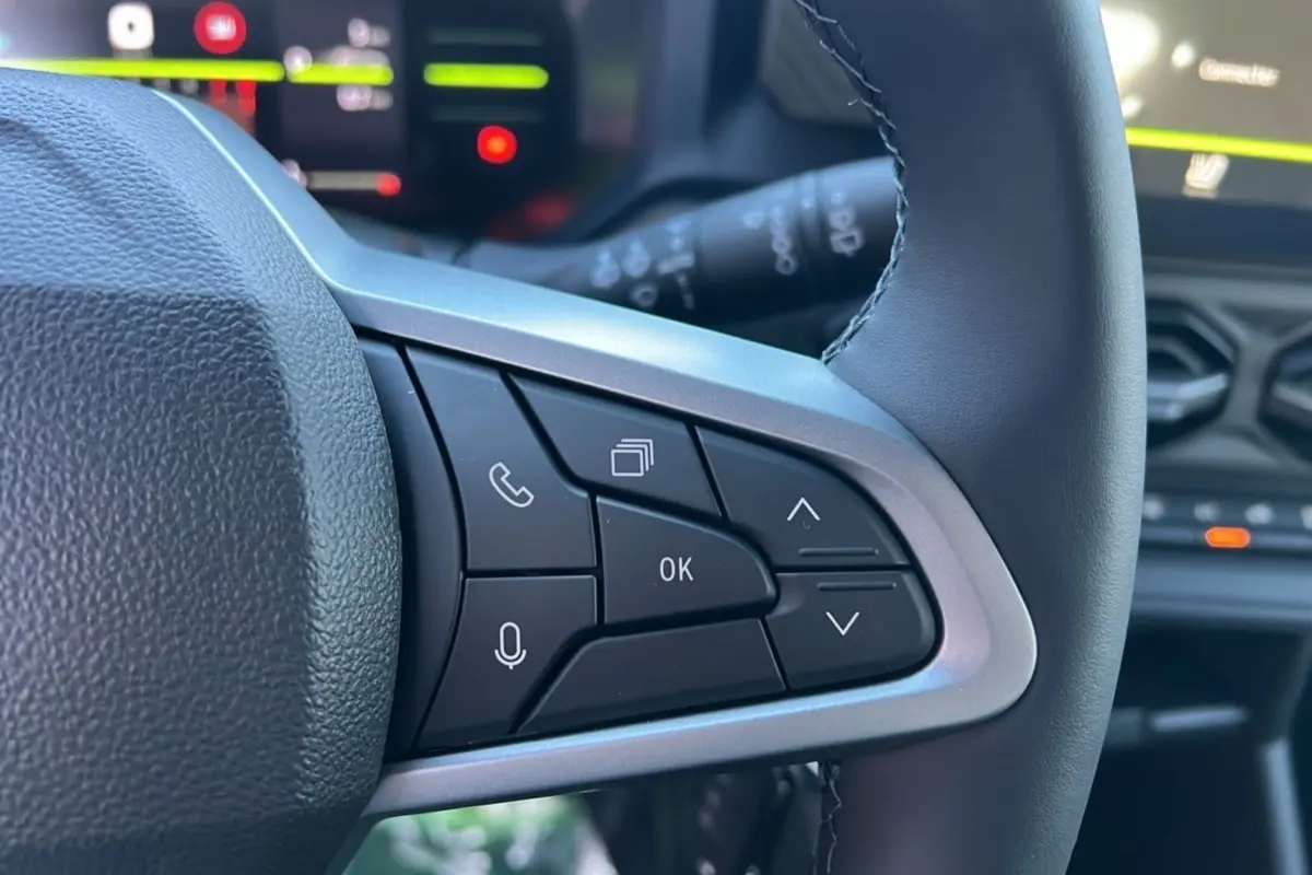 Gros plan sur les commandes au volant du Dacia Duster 2025, version Mild Hybrid 130 4x4 Expression, avec boutons multifonctions noirs.