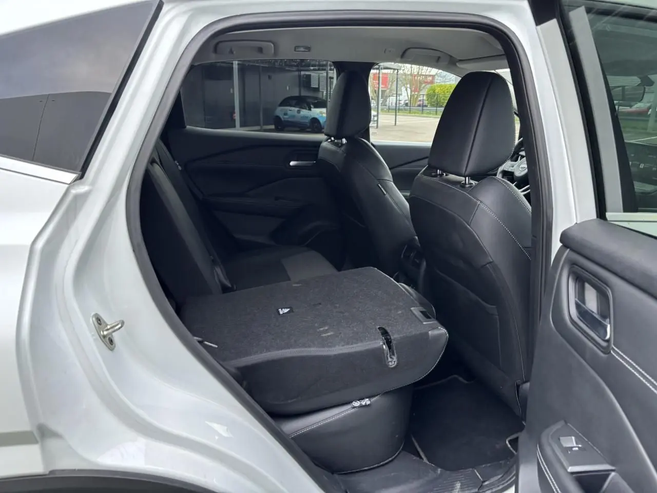 Vue côté gauche arrière du Nissan Qashqai blanc nacré avec banquette arrière rabattue et sellerie noire mixte TEP et tissu.