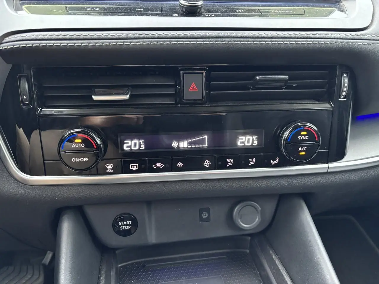 Vue rapprochée de la console centrale noire du Nissan Qashqai blanc nacré 2025, affichant la climatisation automatique bi-zone.