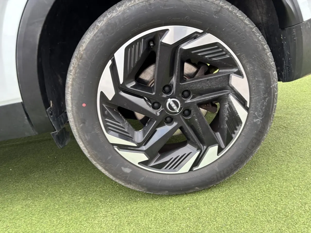 Gros plan sur la jante alliage noire et argent du Nissan Qashqai blanc nacré, côté droit, avec pneu Bridgestone.