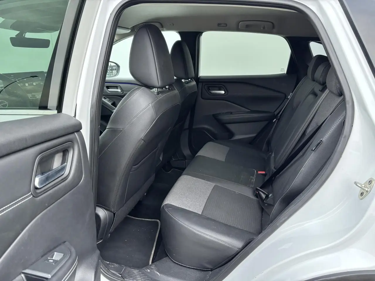 Vue intérieure côté gauche montrant la banquette arrière en sellerie mixte noir du Nissan Qashqai blanc nacré.