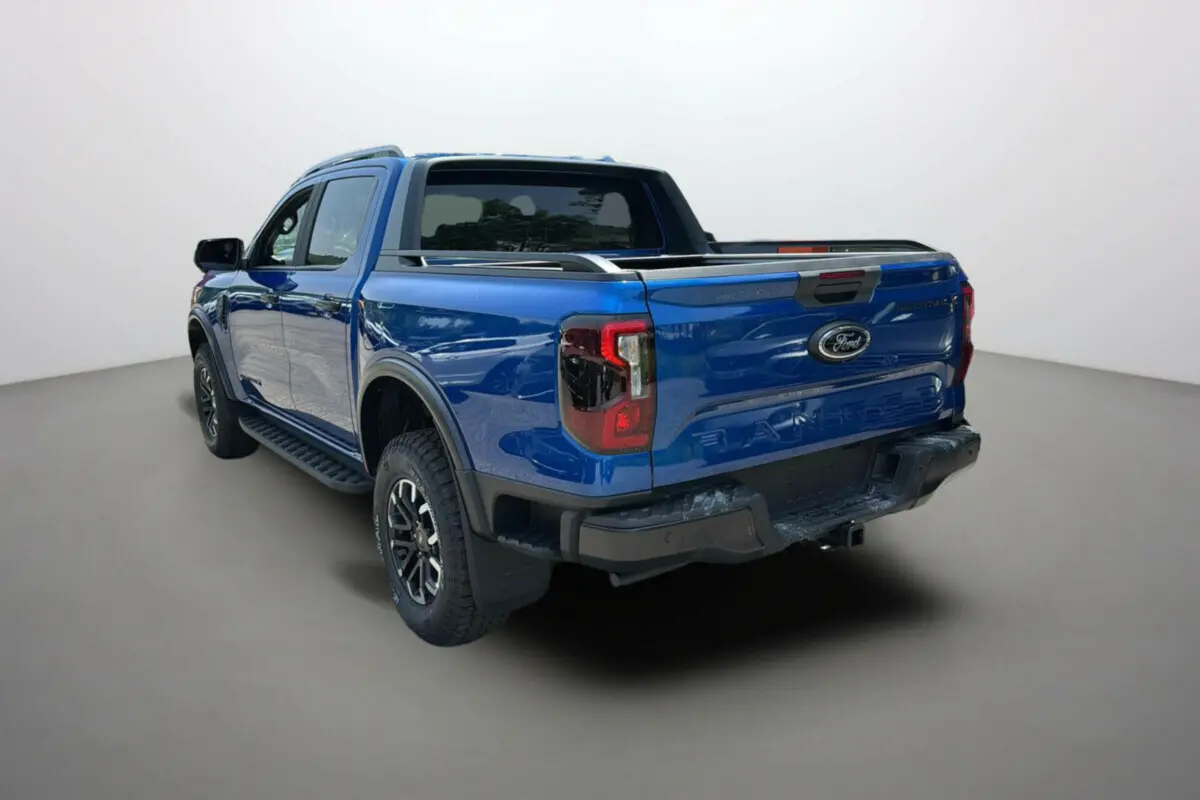 Vue 3/4 arrière droite du Ford Ranger 2025 bleu lightning avec arceau sport et barres de toit visibles.