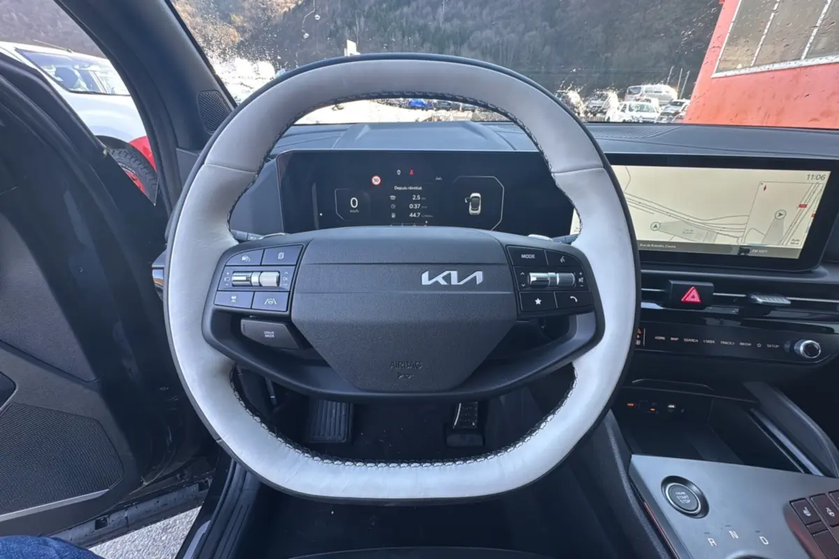 Vue intérieure centrée sur le volant cuir clair du Kia Sportage 2026 avec tableau de bord numérique et écran GPS panoramique.