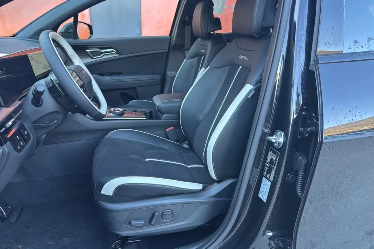 Vue intérieure côté conducteur du Kia Sportage 2026 noir étoilé, sièges sport cuir et alcantara avec surpiqûres blanches.