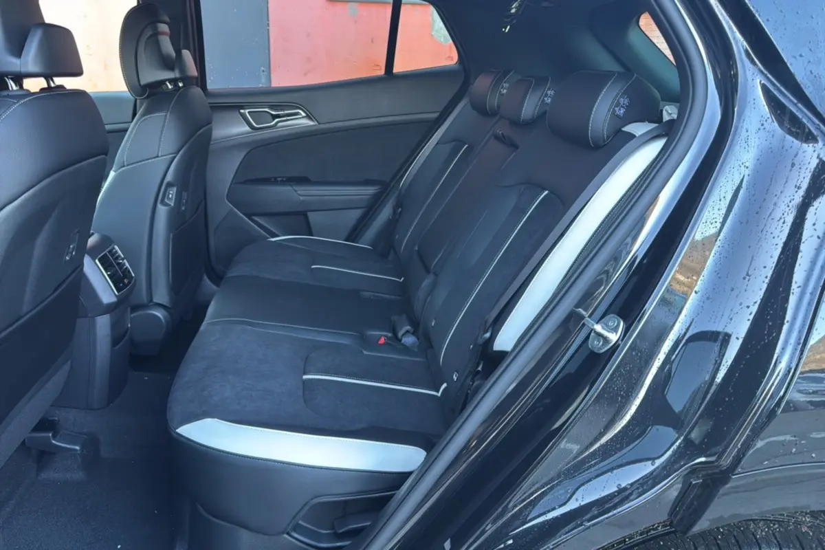 Vue intérieure côté droit sur la banquette arrière noire et grise du Kia Sportage 2026 avec porte ouverte et sellerie mixte cuir/alcantara.