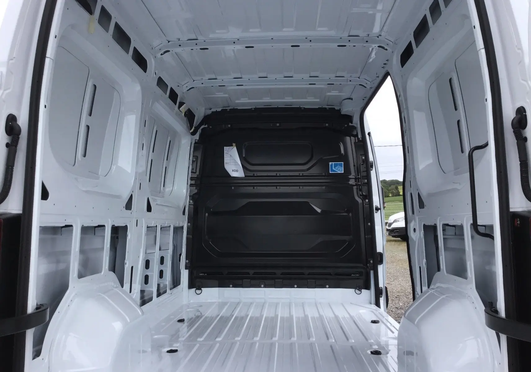 Vue intérieure arrière du Renault Master blanc L2H2 2025, montrant l'espace de chargement vide avec cloison noire.