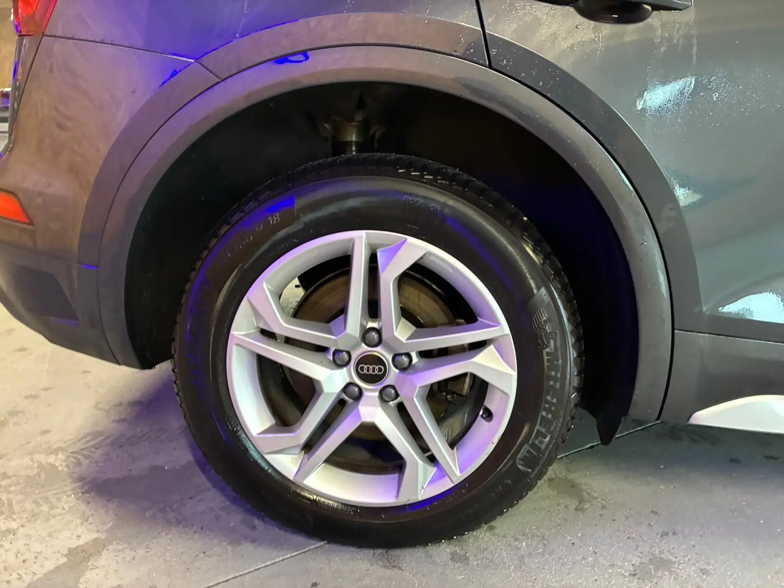 Gros plan sur la roue arrière droite d’un Audi Q5 gris 2024 avec jante aluminium 5 branches doubles.