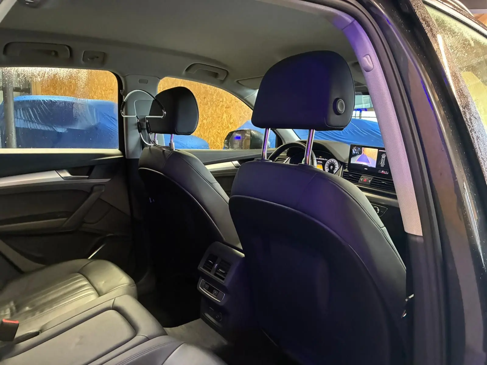 Vue intérieure arrière côté droit de l'Audi Q5 2024 gris, montrant les sièges en cuir noir et la console centrale avec commandes.