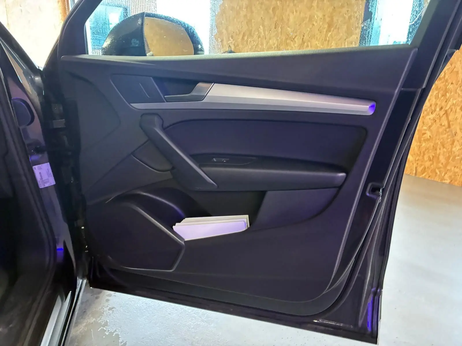 Vue intérieure de la porte avant gauche gris foncé de l'Audi Q5 2024 avec insert argenté et rangement inférieur.