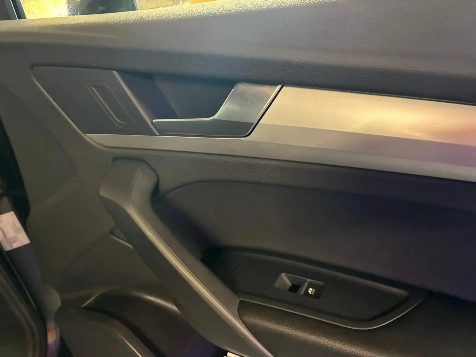 Détail de la porte intérieure côté gauche de l’Audi Q5 2024 avec insert argent et commande de vitre noire.