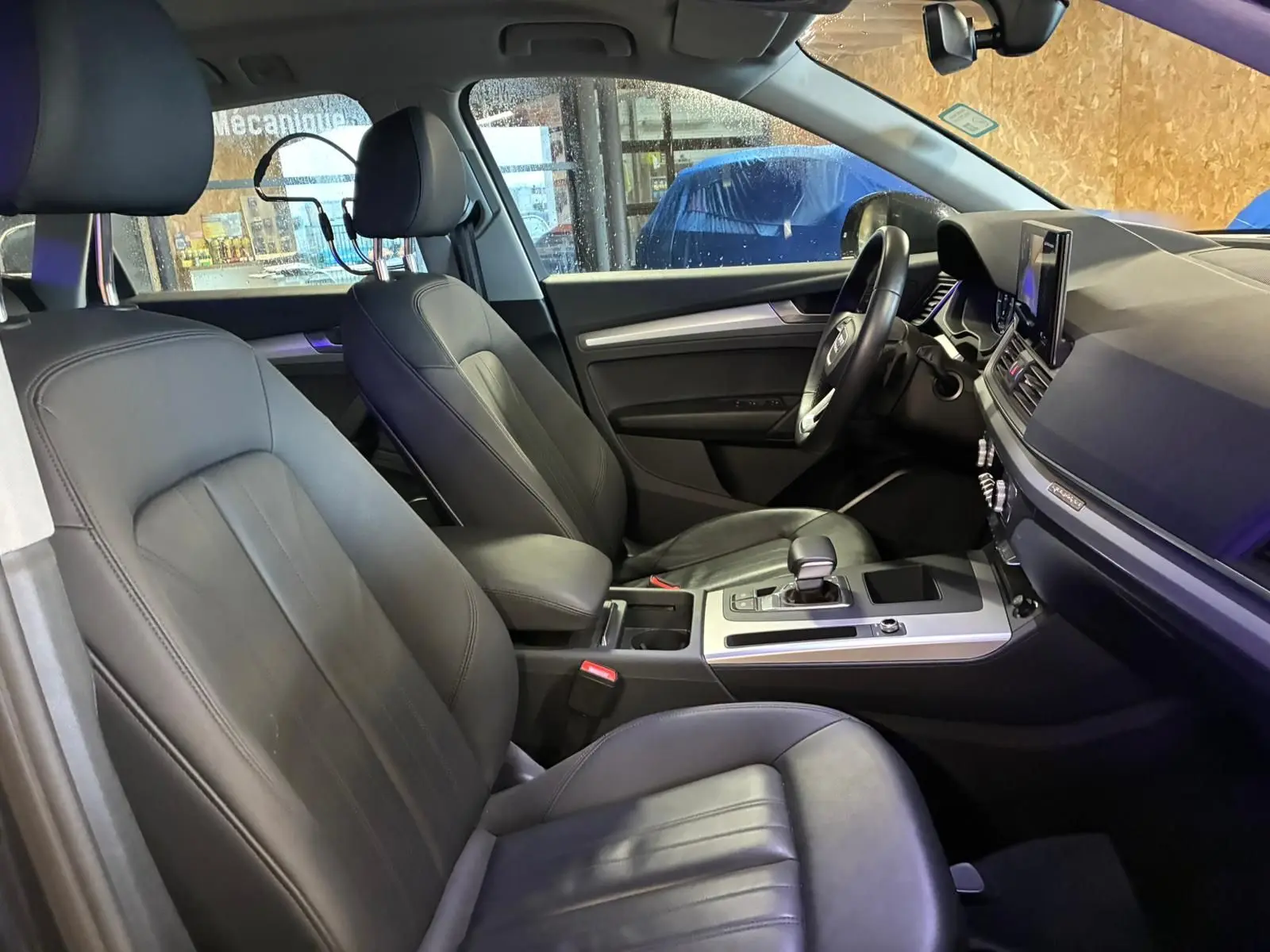 Vue intérieure côté conducteur de l'Audi Q5 2024, sièges en cuir noir et console centrale avec levier de vitesses.