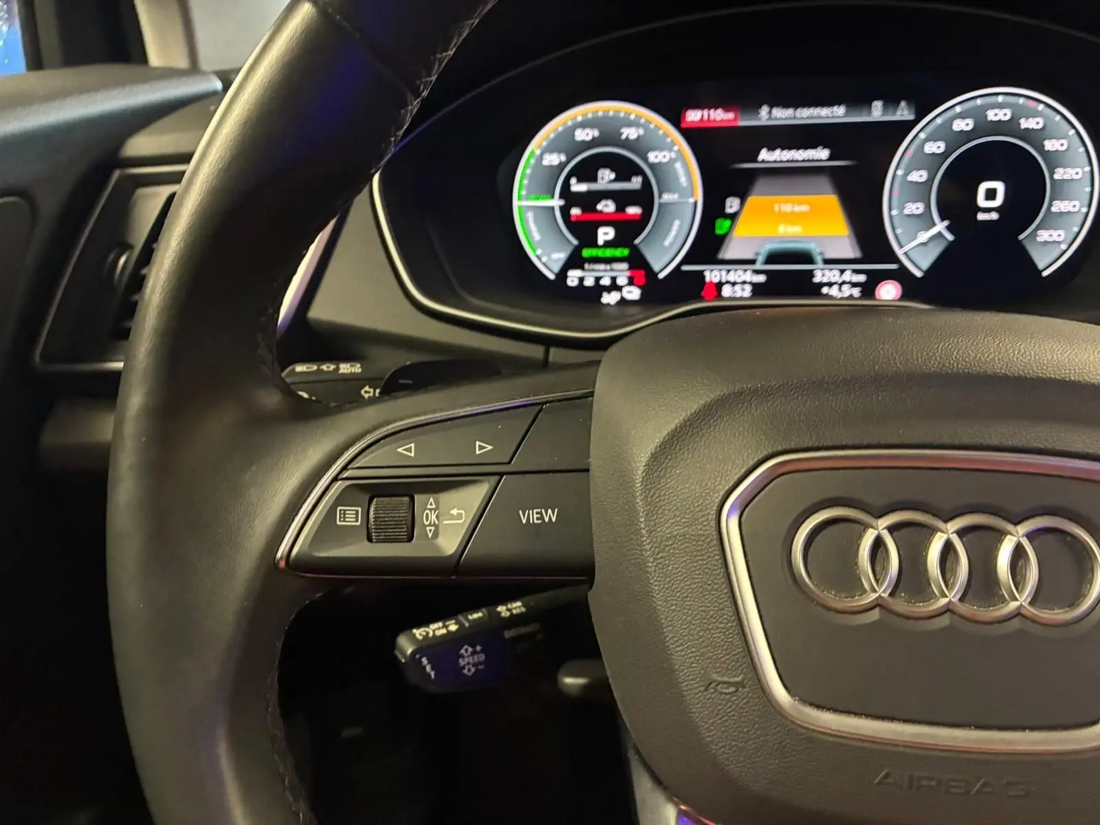 Vue rapprochée du volant cuir noir et du tableau de bord numérique de l'Audi Q5 gris 2024 hybride rechargeable.