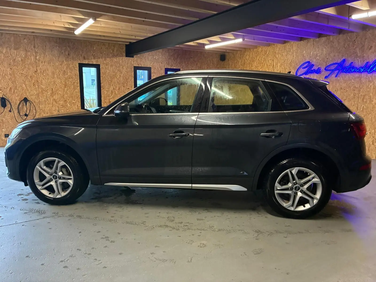 Audi Q5 hybride rechargeable gris en vue de profil côté gauche, avec jantes 5 branches doubles et passages de roue noirs.