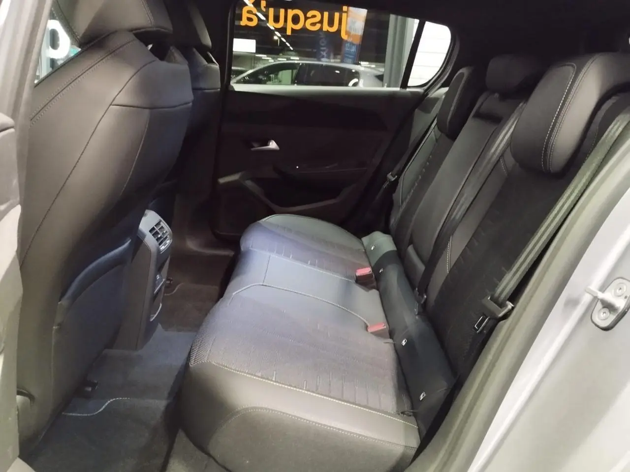 Vue côté droit de l’habitacle arrière de la Peugeot 308 gris Artense, montrant les sièges et les finitions intérieures.
