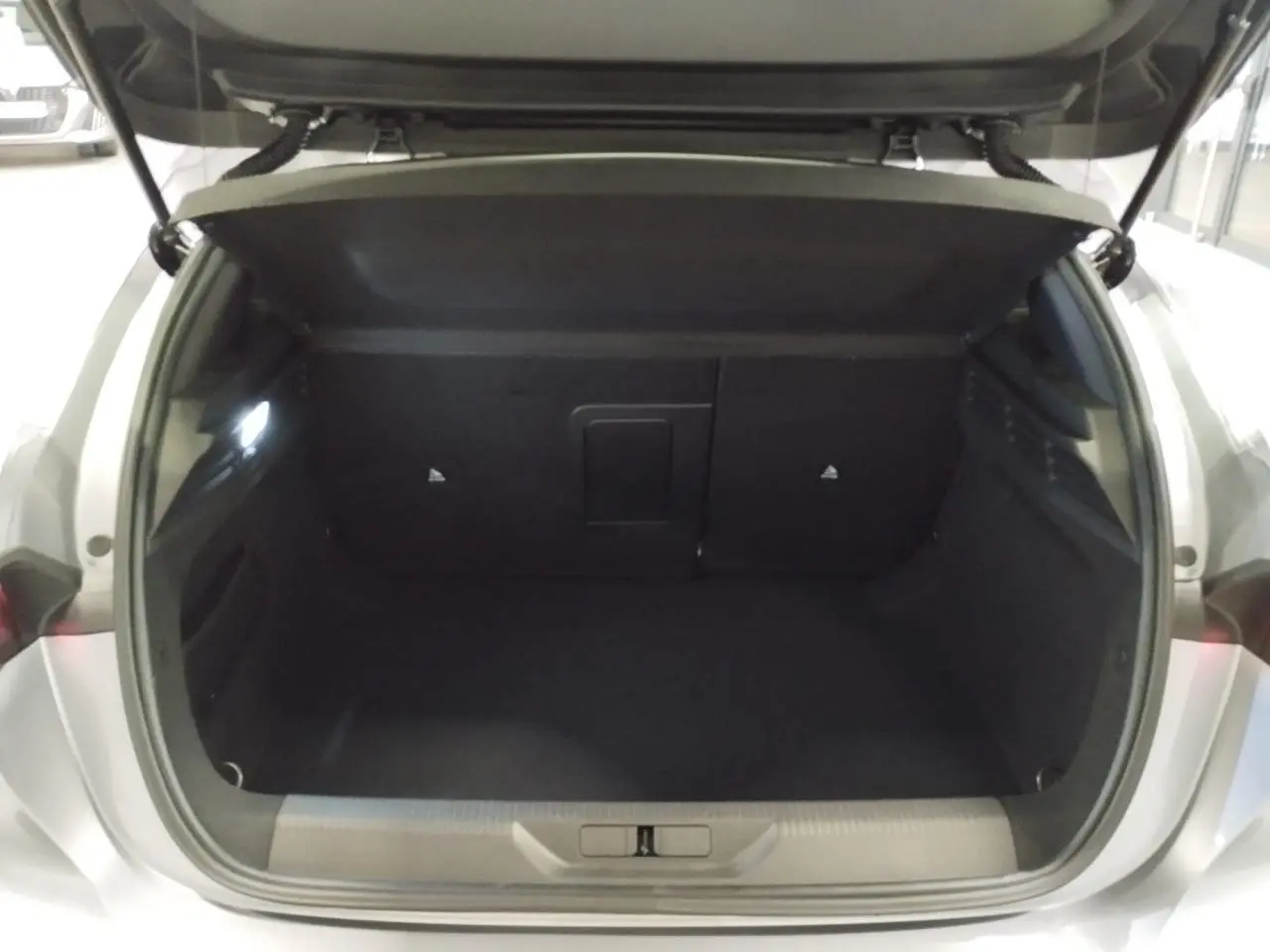 Coffre ouvert vu de l'arrière d'une Peugeot 308 gris Artense, montrant l'espace de chargement vide et l'éclairage intérieur.