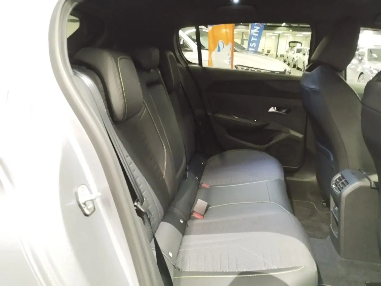 Vue intérieure de la banquette arrière noire avec surpiqûres vert Adamite dans une Peugeot 308 gris Artense.