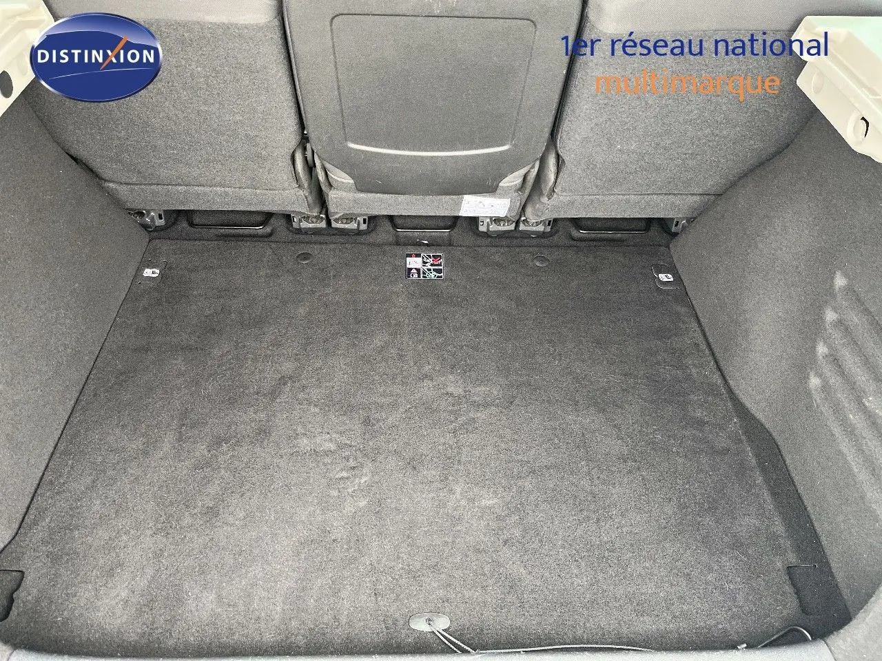 Coffre spacieux et propre de Renault Scénic III gris, vue plongeante sur l’espace de chargement avec sièges arrière rabattus.