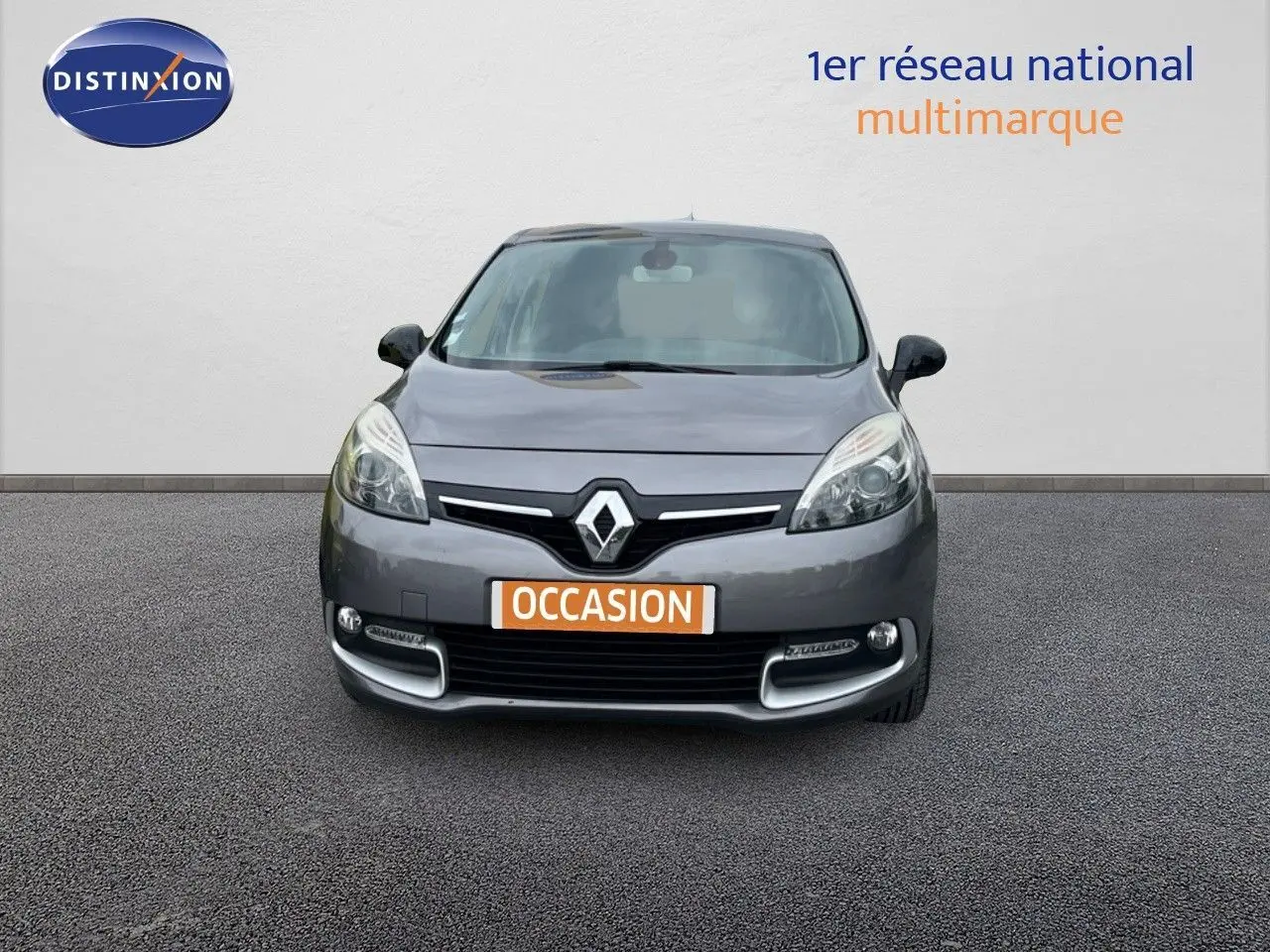 Vue avant d'une Renault Scénic III gris métallisé avec logo Renault bien visible sur fond neutre.