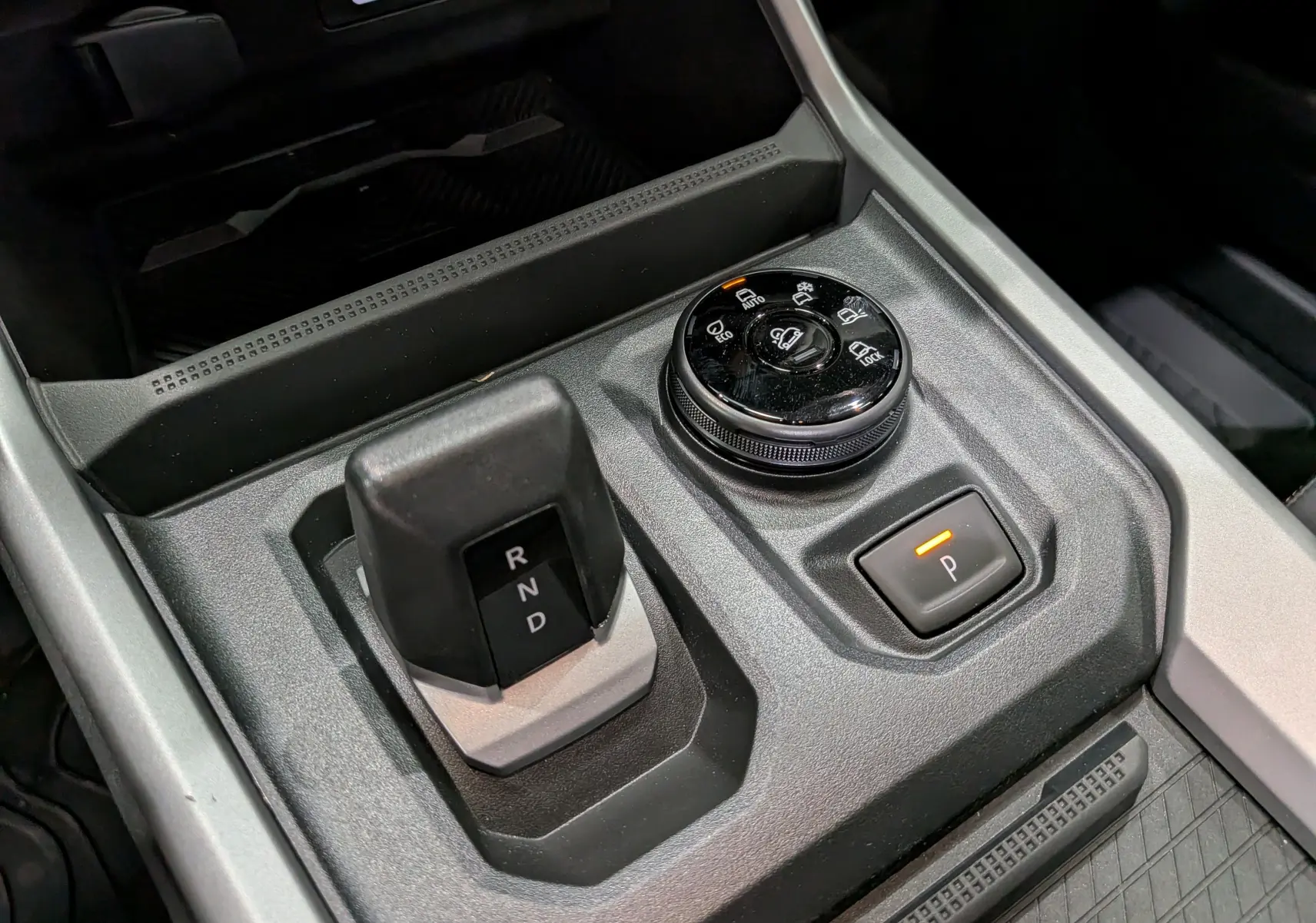 Gros plan sur la console centrale du Dacia Bigster Hybrid-G 150 4x4, montrant la commande de boîte auto et le sélecteur de modes de conduite.