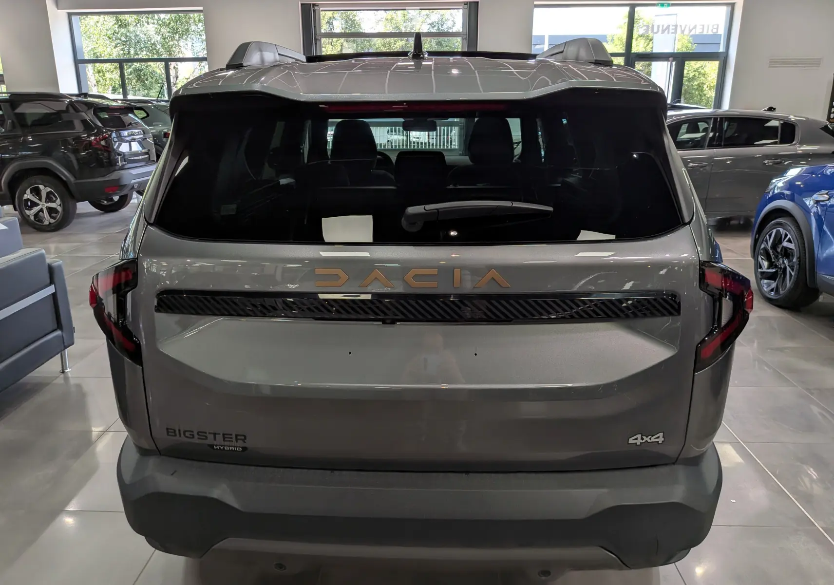 Vue arrière du Dacia Bigster Hybrid-G 150 4x4 gris schiste, avec logo Dacia doré et feux arrière LED distinctifs.