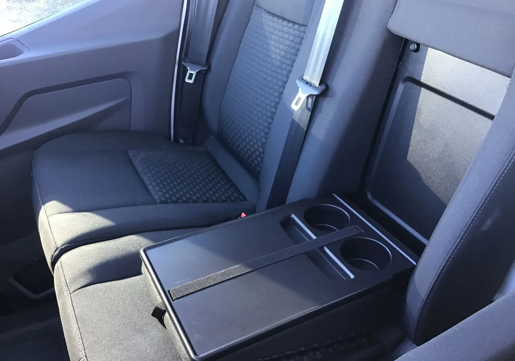 Vue rapprochée de la banquette avant grise avec accoudoir central et porte-gobelets du Ford Transit Châssis Cabine blanc.