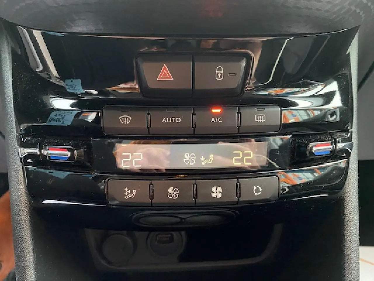 Vue rapprochée du tableau de bord de la Peugeot 2008 blanc, montrant la commande de climatisation automatique bi-zone à 22°C.