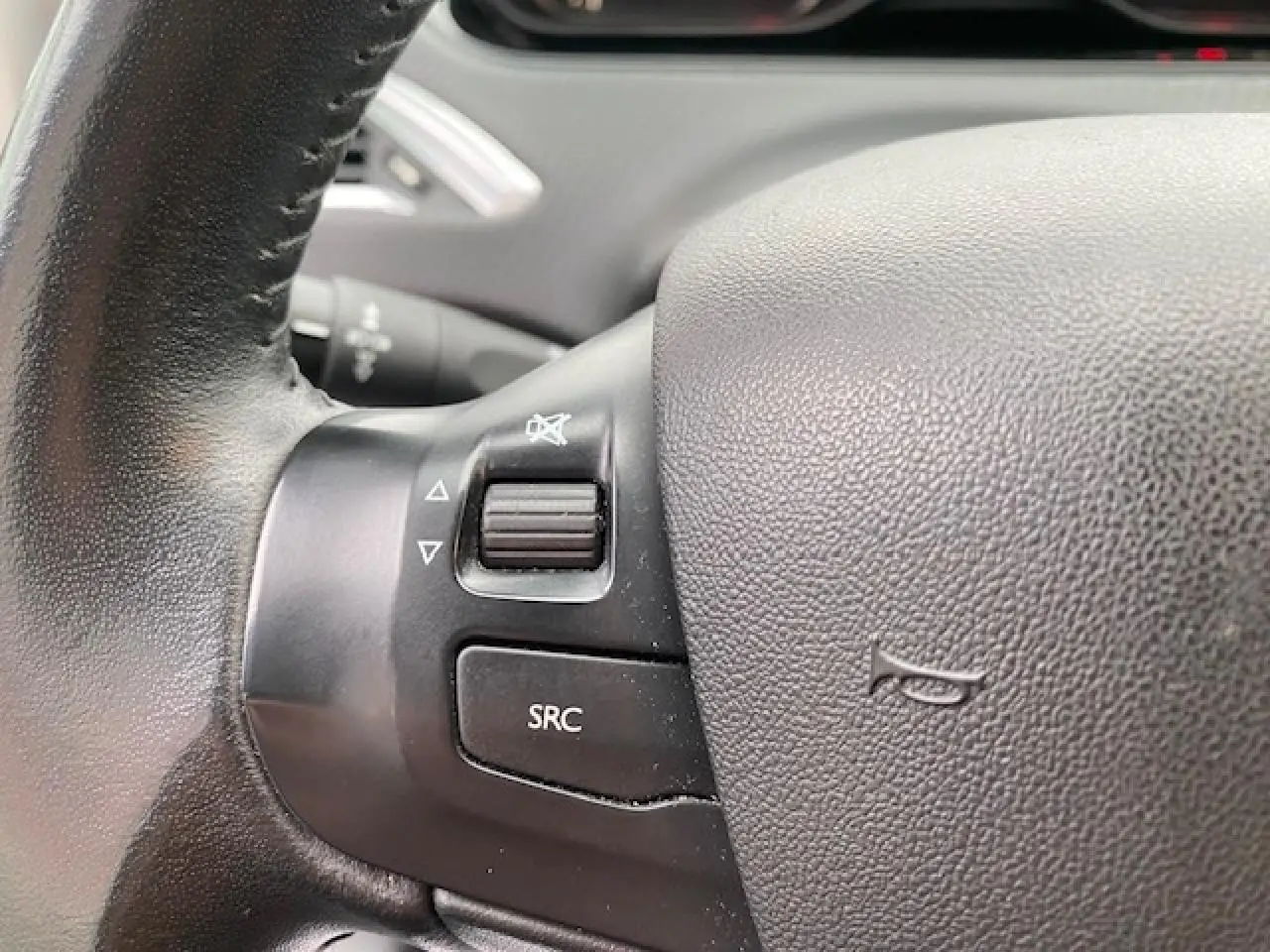 Gros plan sur les commandes audio au volant noir du Peugeot 2008 blanc, version Style Phase 2 de 2018.