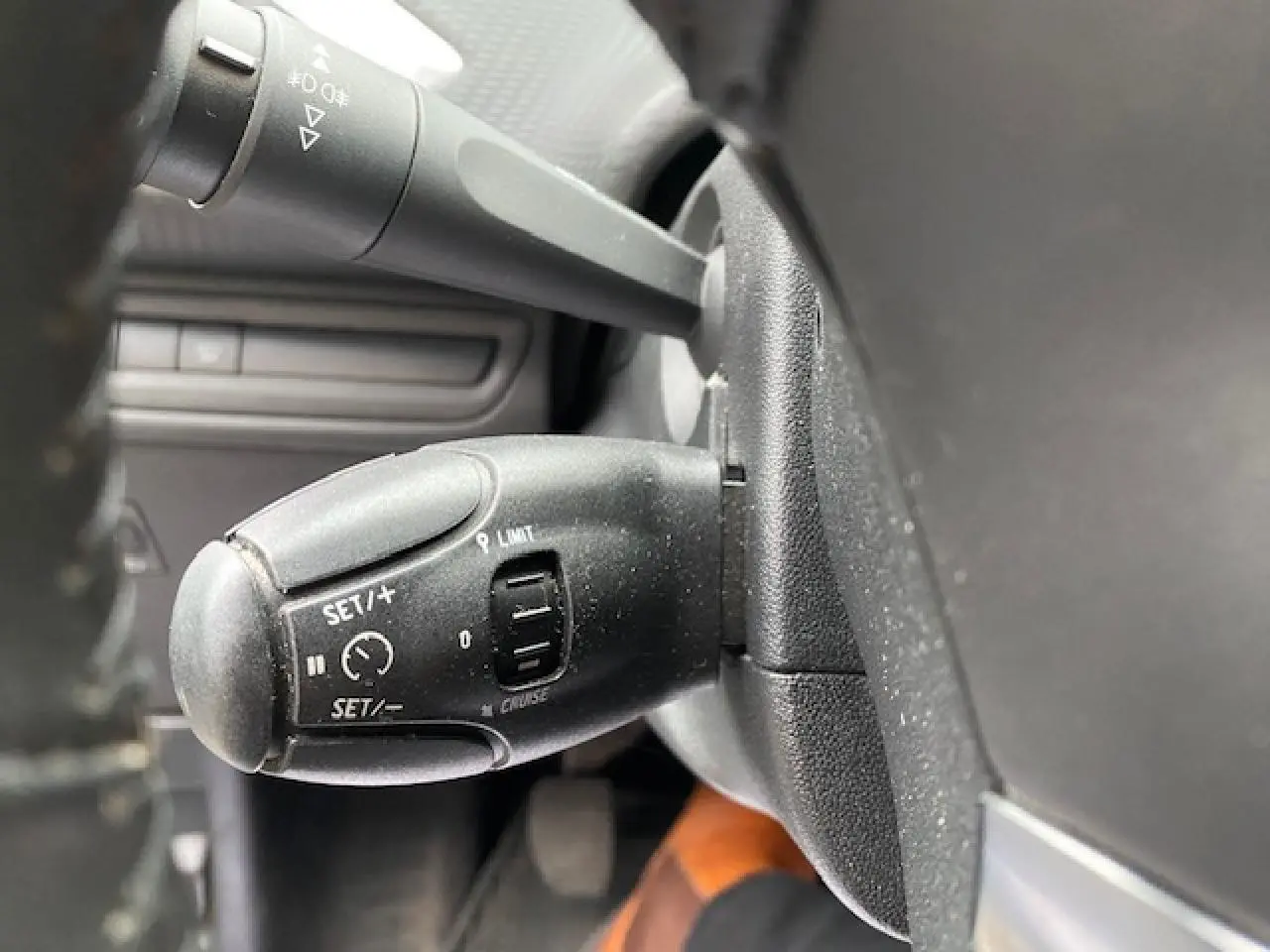 Gros plan sur la commande de régulateur de vitesse à gauche du volant d'un Peugeot 2008 blanc de 2018.