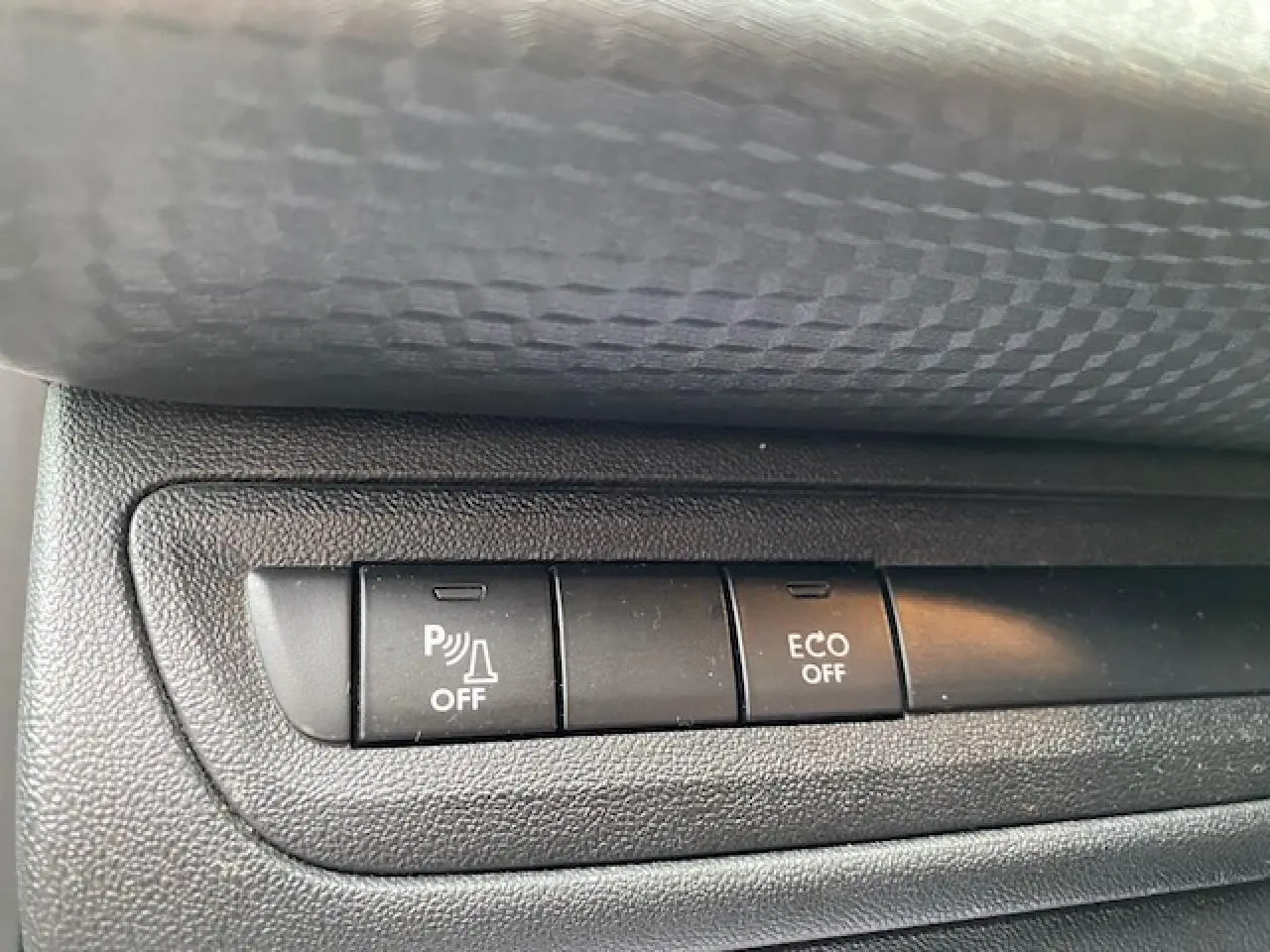 Gros plan sur les boutons de commande du système d'aide au stationnement et mode ECO de la Peugeot 2008 blanche.