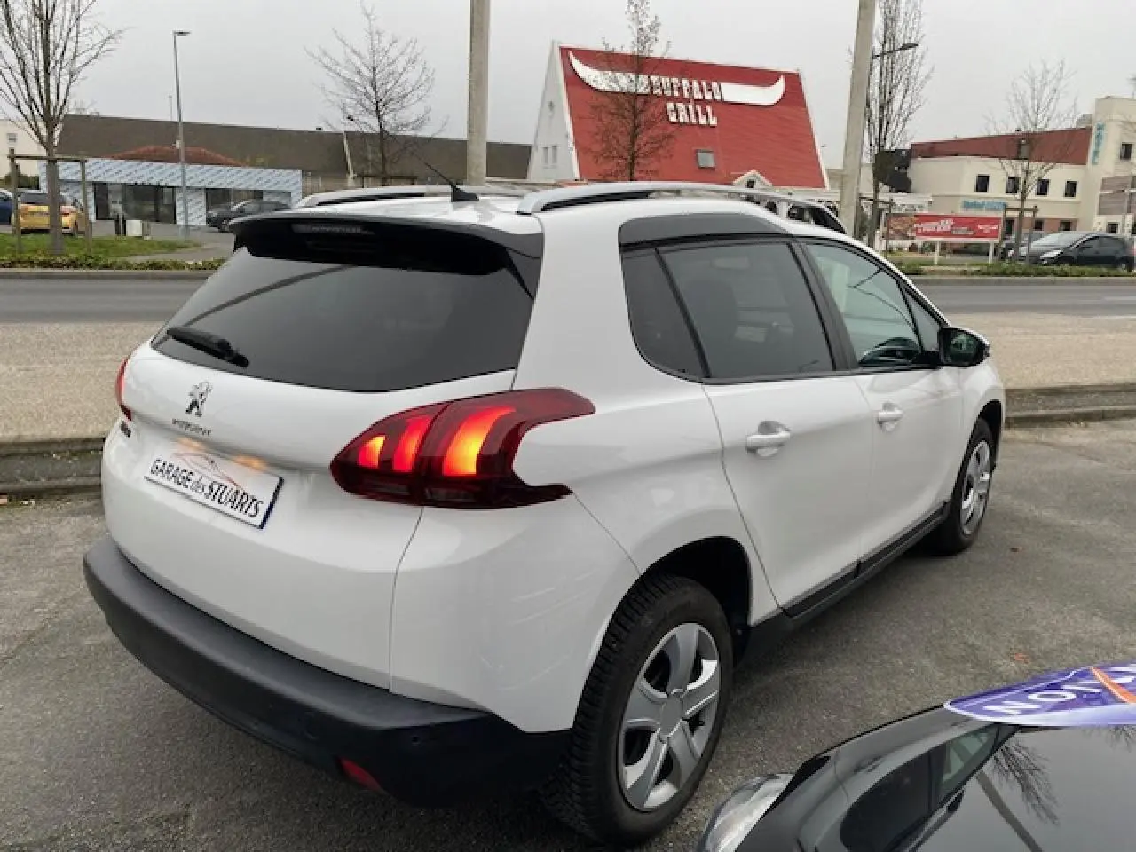 Vue 3/4 arrière droite d'un Peugeot 2008 blanc avec feux arrière à griffes 3D LEDs et vitres surteintées.