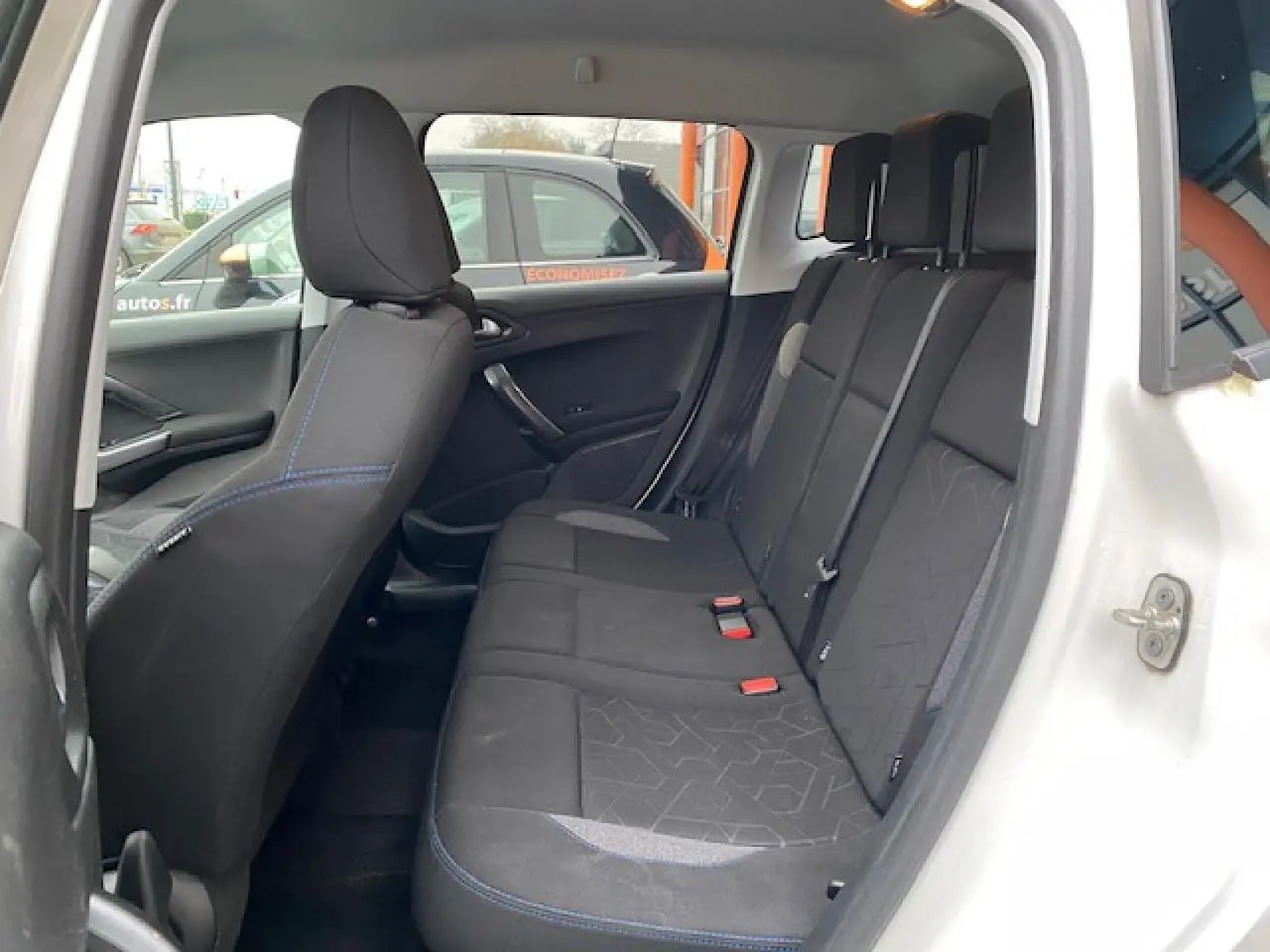 Vue intérieure côté gauche sur la banquette arrière noire du Peugeot 2008 blanc avec détails de couture bleue.