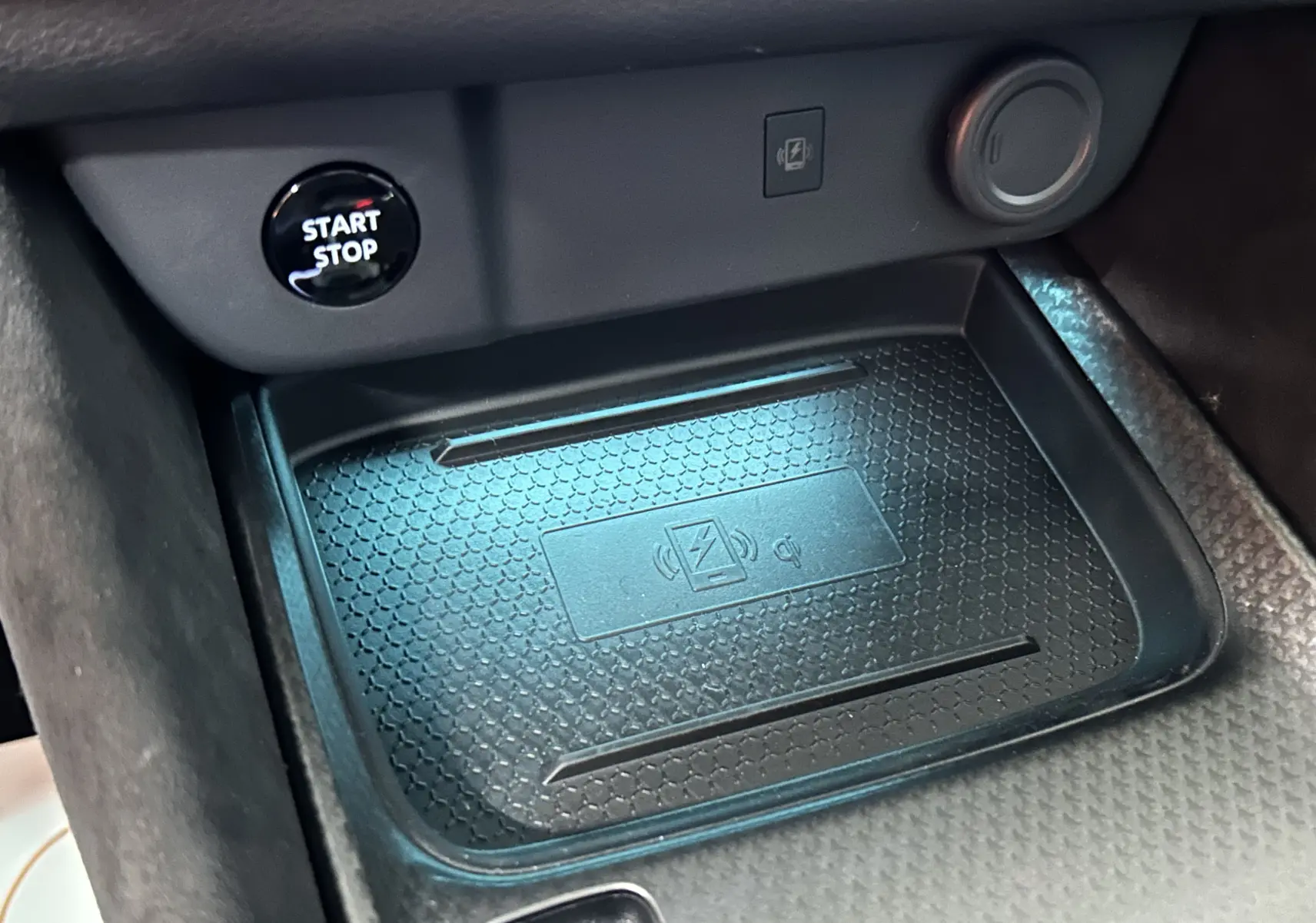 Gros plan sur la zone de recharge sans fil et bouton start/stop dans l'habitacle noir du Nissan Qashqai 2025.
