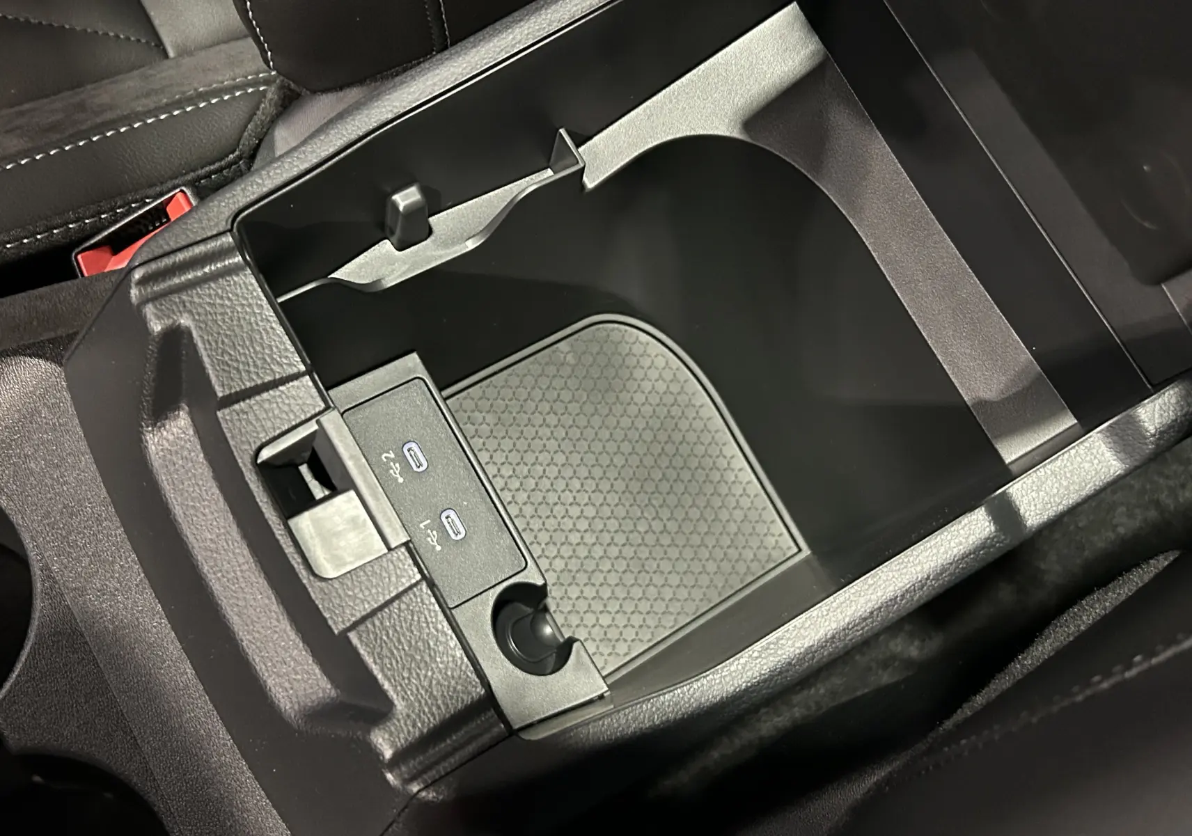 Vue rapprochée de la console centrale ouverte du Nissan Qashqai 2025, avec ports USB et intérieur noir.