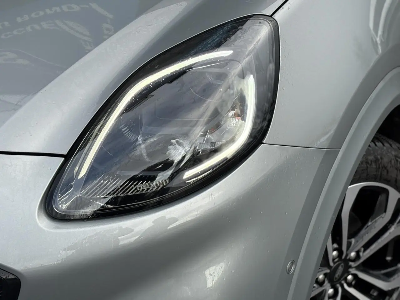 Gros plan sur le phare avant gauche et la jante alliage 17 pouces du Ford Puma gris Solar 2023.