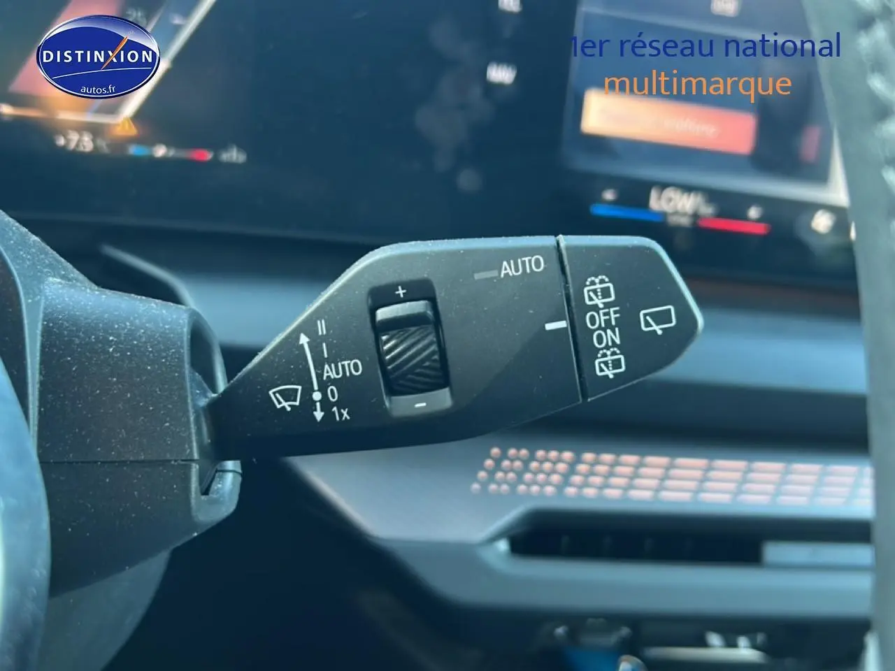 Gros plan sur la commande des essuie-glaces dans l'habitacle d'une BMW Série 1 blanche, tableau de bord en arrière-plan.