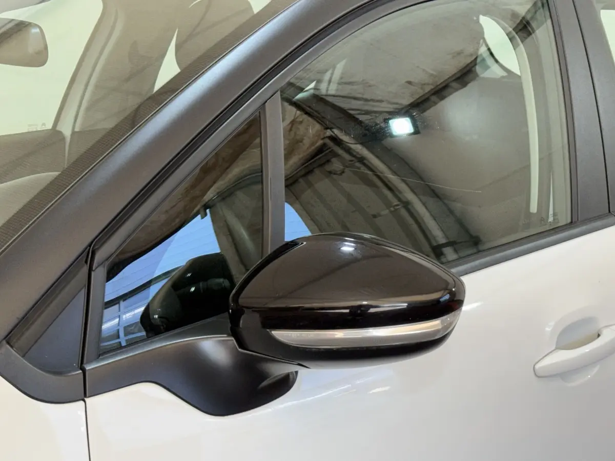Gros plan sur le rétroviseur noir côté conducteur d'une Citroën C3 blanche vue de profil gauche.
